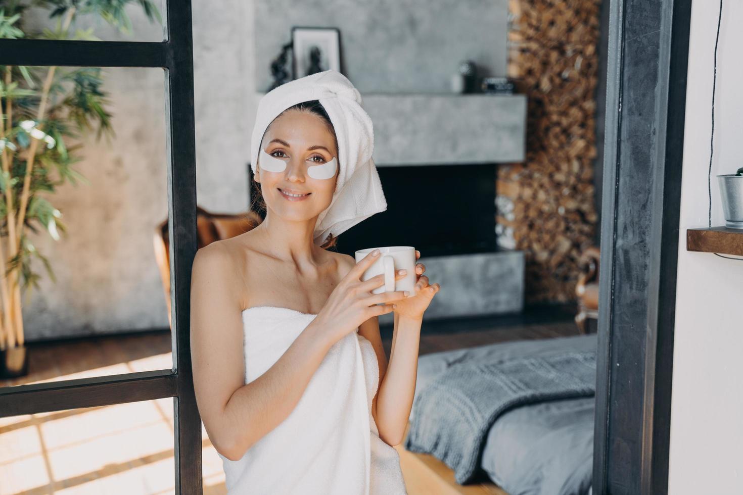 garota aplica tapa-olhos de levantamento relaxante com uma xícara de chá. manhã de fim de semana no luxuoso spa resort. foto