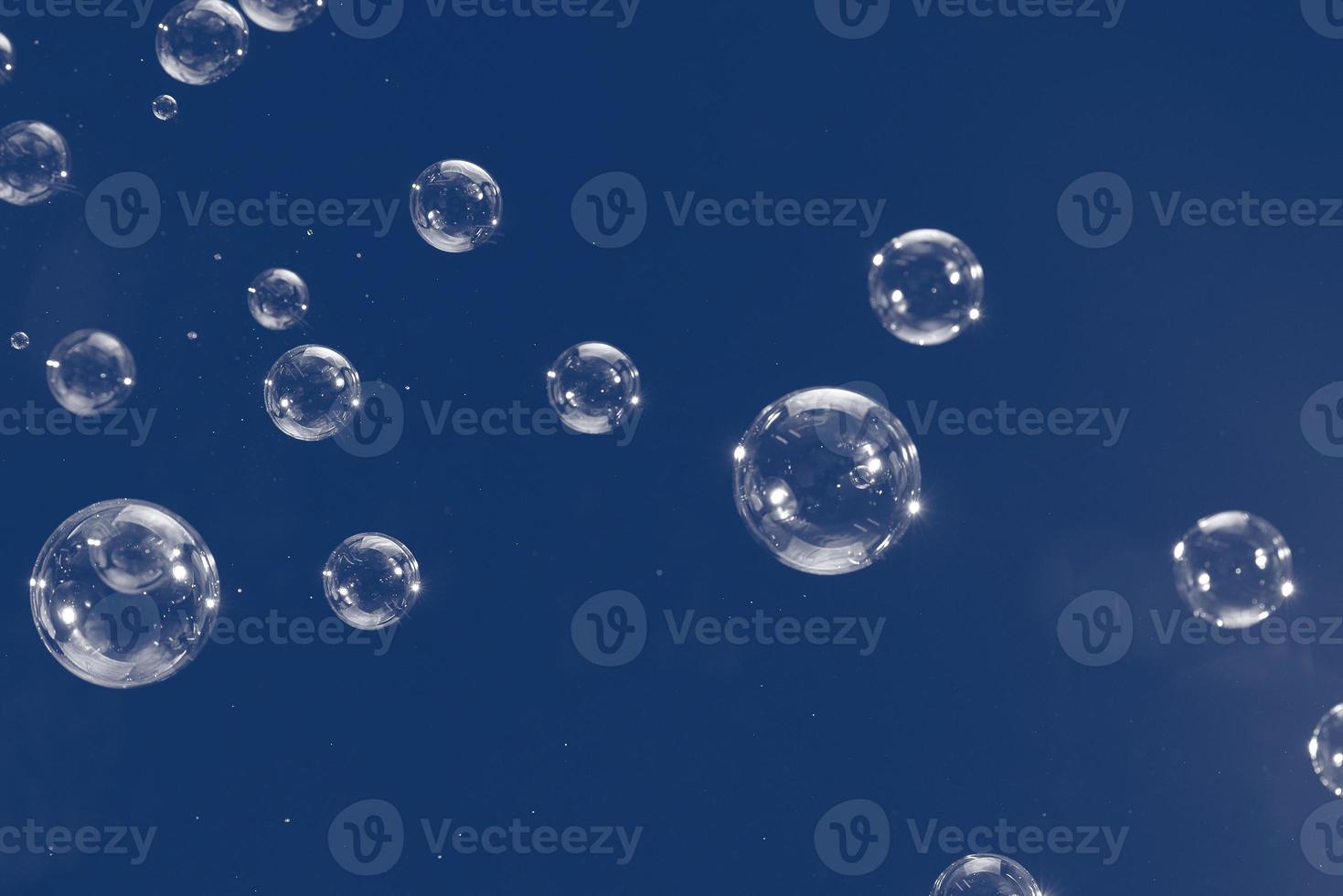 bolhas de sabão voadoras isoladas em fundo azul. abstrato. foto