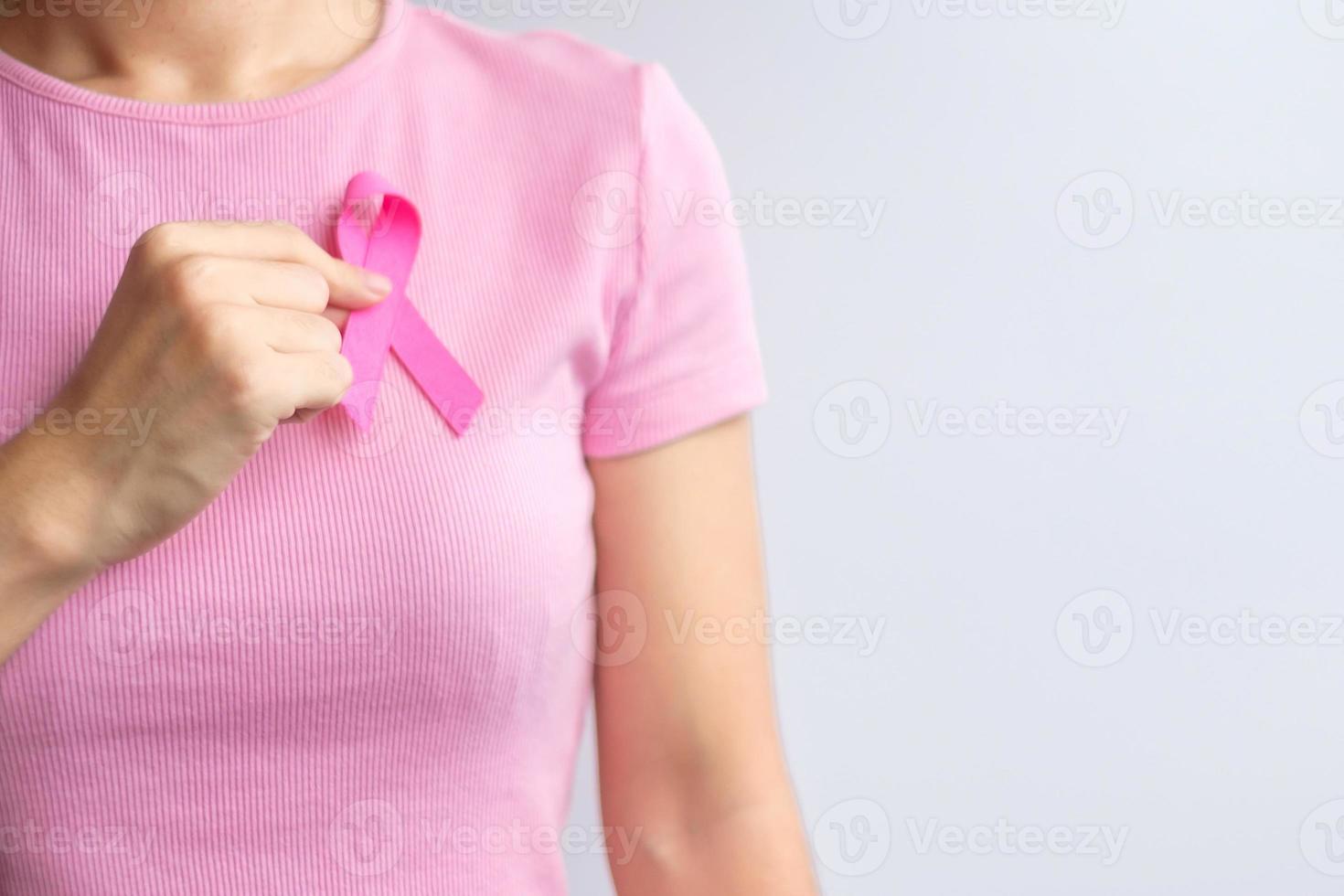 mês de conscientização do câncer de mama de outubro rosa, a mão da mulher segura a fita rosa e usa camisa para apoiar a vida e a doença das pessoas. mês nacional de sobreviventes de câncer, mãe e conceito de dia mundial do câncer foto