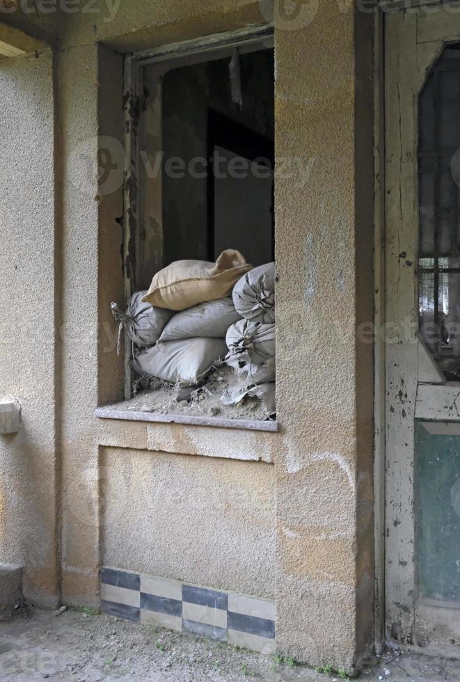 sacos de areia empilhados em uma janela de uma casa na linha verde da zona tampão em nicosia, chipre foto