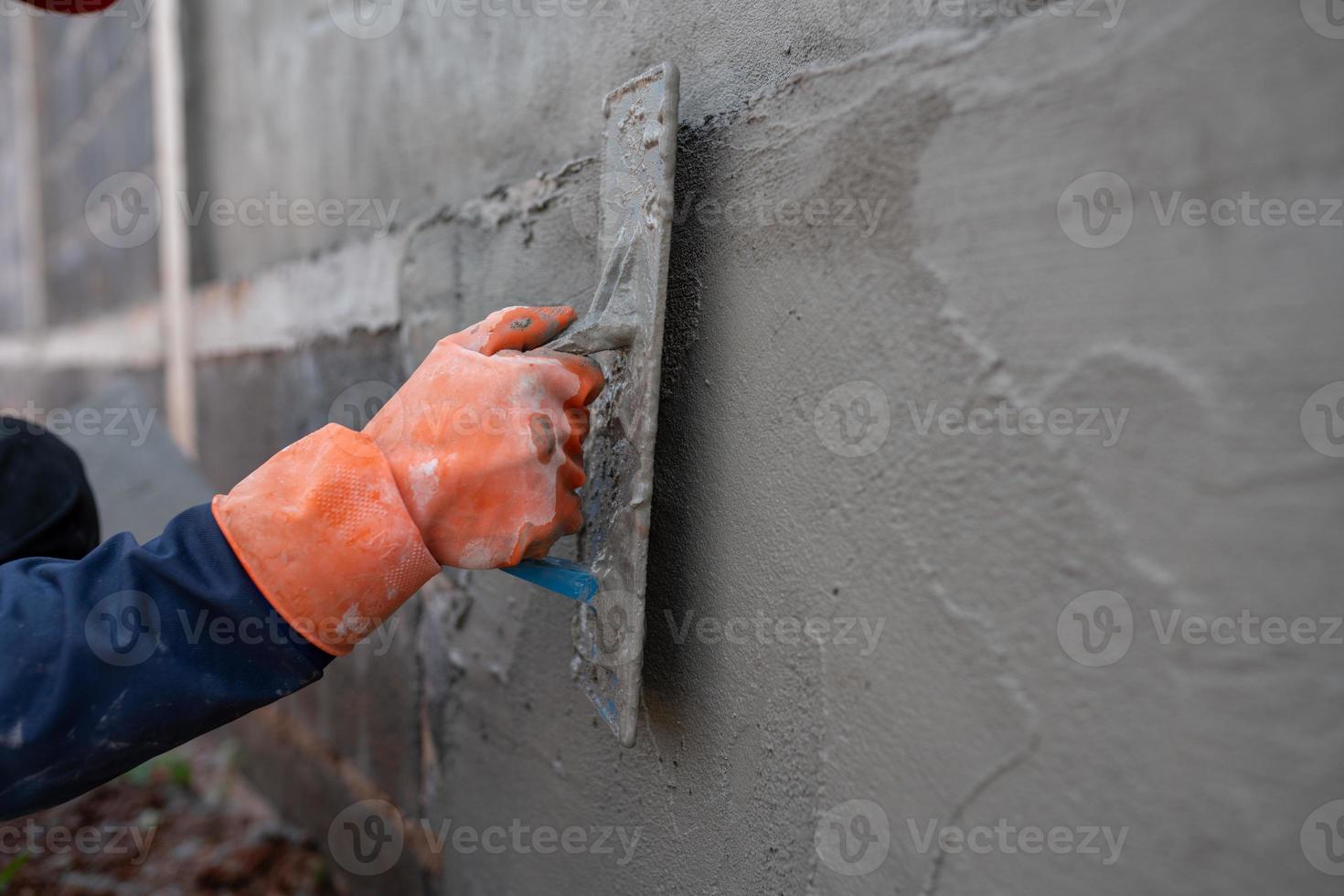 os trabalhadores de alvenaria usam espátulas de cimento em canteiros de obras. foto