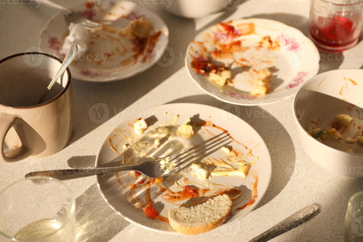 pratos sujos vazios com colheres e garfos na mesa após a refeição. conceito de final de banquete. pratos sujos foto