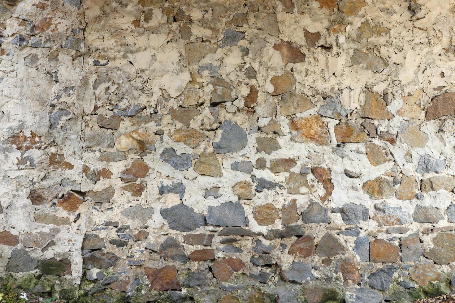 textura de uma parede de pedra com muitas grandes pedras marrons e cinzentas armadas com cimento. antigo fundo de textura de parede de pedra do castelo para uso medieval. parte de um edifício pedregoso foto