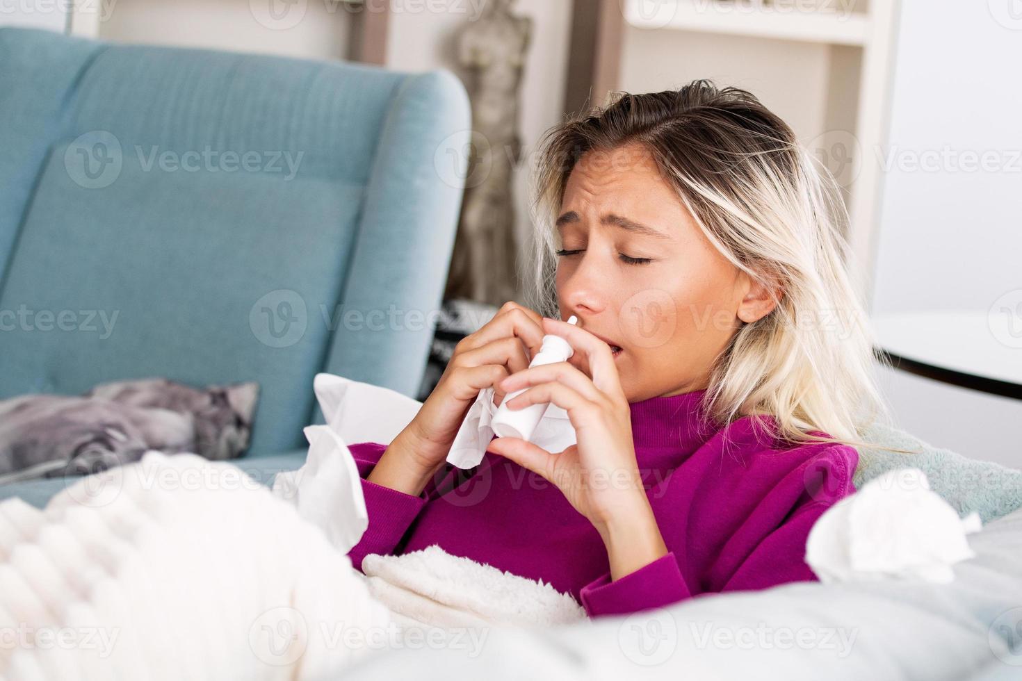 mulher está com gripe e está usando spray nasal para se ajudar. mulher usando spray nasal. spray nasal para ajudar um resfriado. doente com uma mulher com rinite pingando nariz. mulher aplica spray nasal foto