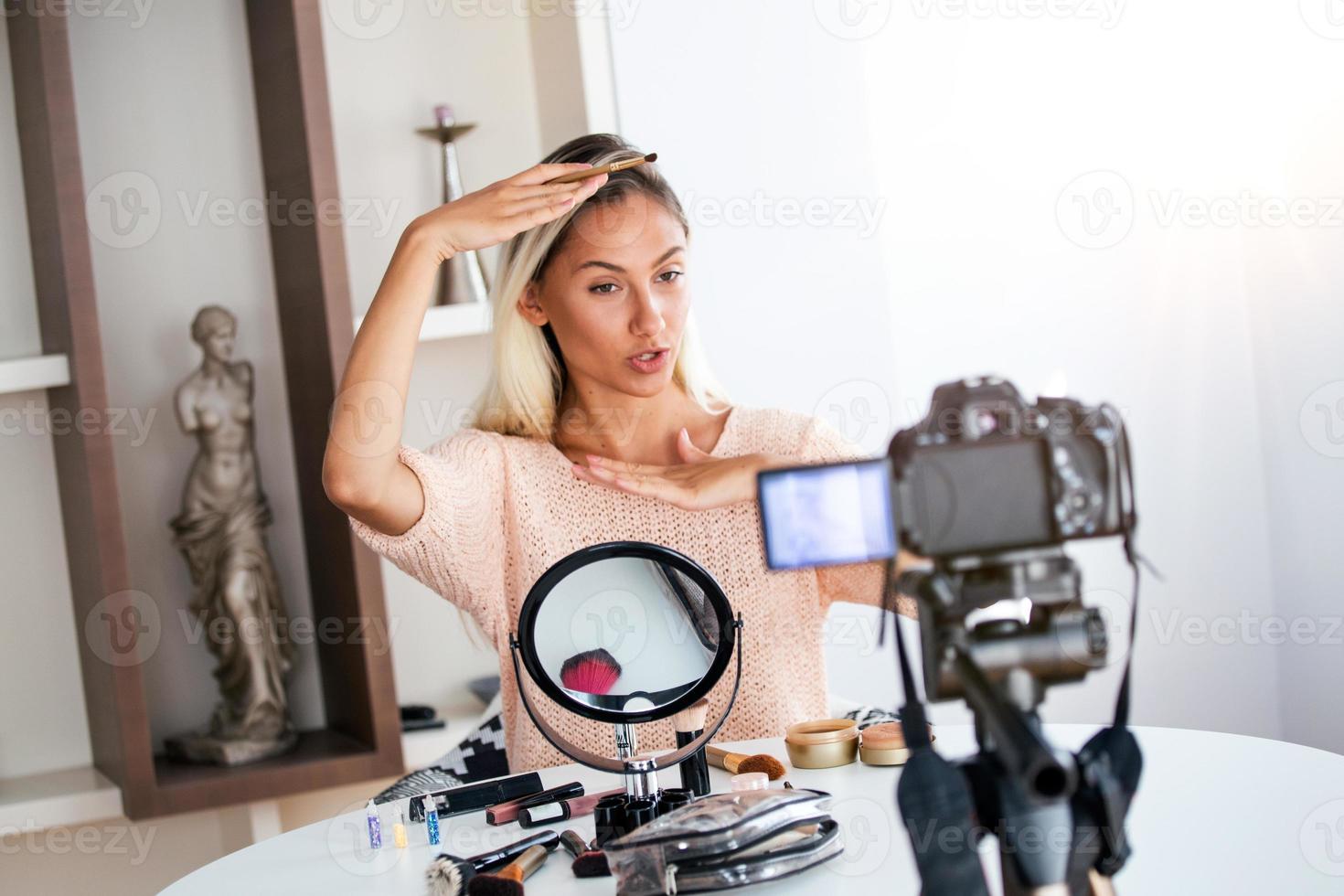 jovem linda loira vlogger de beleza profissional ou blogger gravando tutorial de maquiagem para compartilhar nas mídias sociais foto