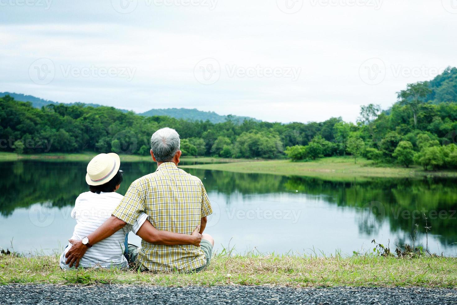 casal asiático com idade abraçando alegremente. ver bela natureza. há montanhas e água doce. foto