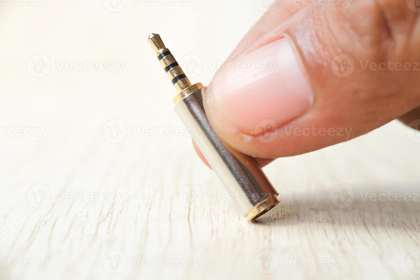 Conector de áudio de dois canais de 3,5 mm a 2,5 mm em mãos masculinas asiáticas foto