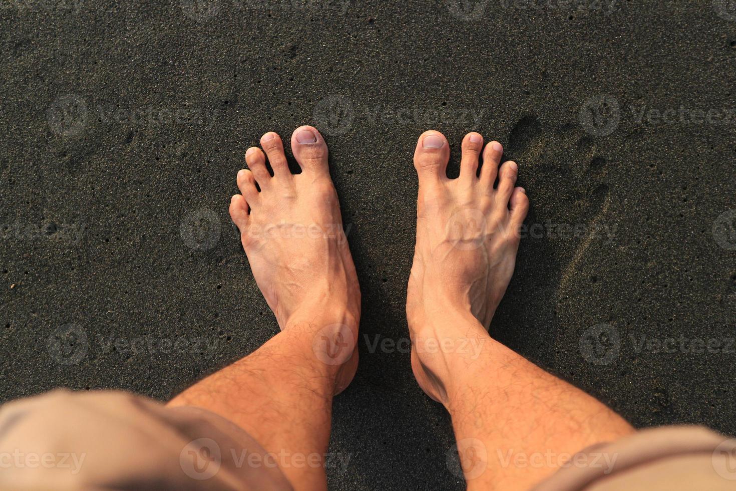 dois pés na praia. com praia de areia preta marrom foto