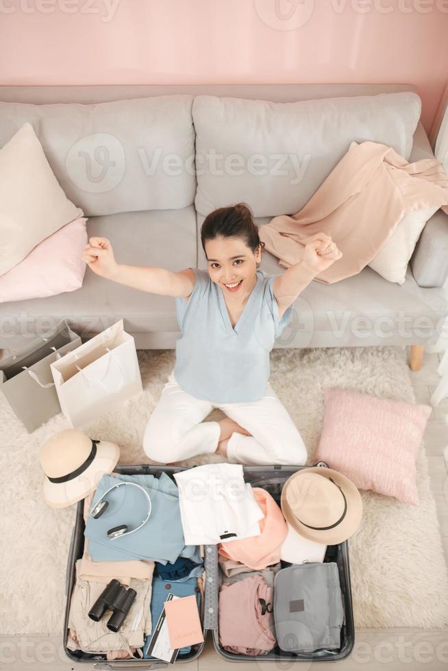 mulher feliz está fazendo uma mala em casa foto