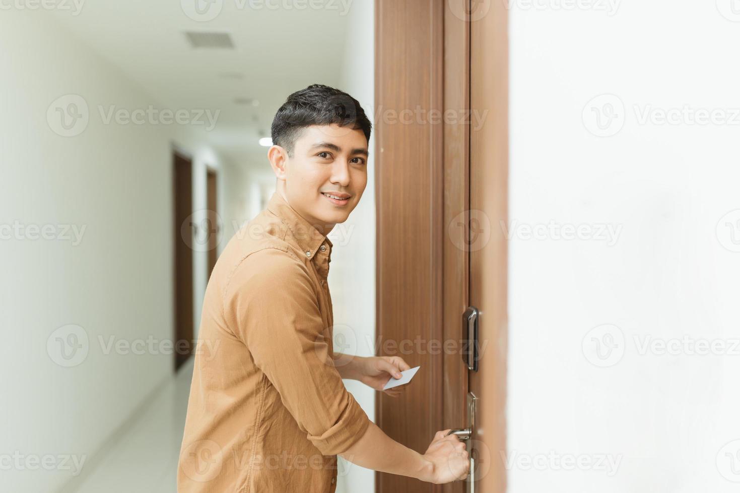 jovem segurando um cartão-chave na frente do sensor eletrônico de uma porta de quarto foto