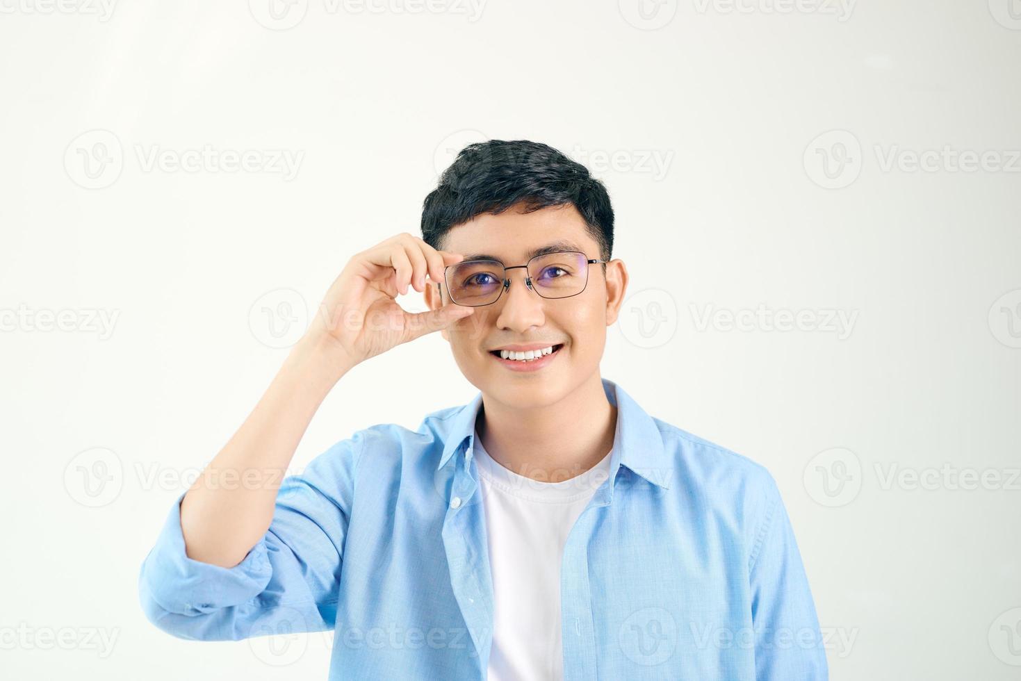 closeup de cara amigável usando óculos. jovem asiático ajustando os óculos e olhando para a câmera através da lente. conceito de visão e cuidados com os olhos foto