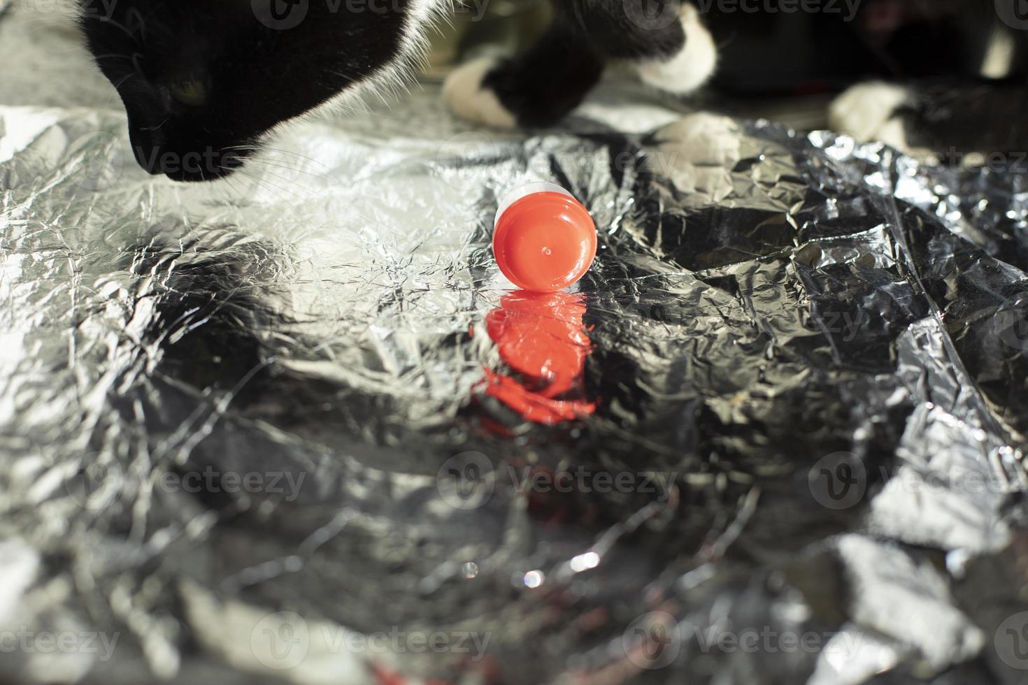 tampa vermelha repousa sobre papel alumínio e passadeiras. reflexão do objeto na camada de metal. foto
