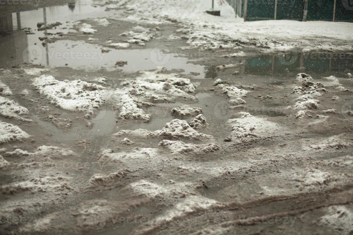 poça de lama de neve derretida na estrada. estacionamento sujo. foto