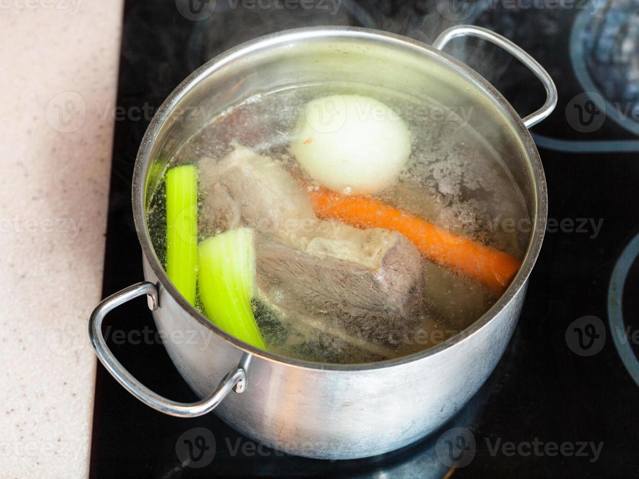 caldo de carne fervendo na panela no fogão de cerâmica foto