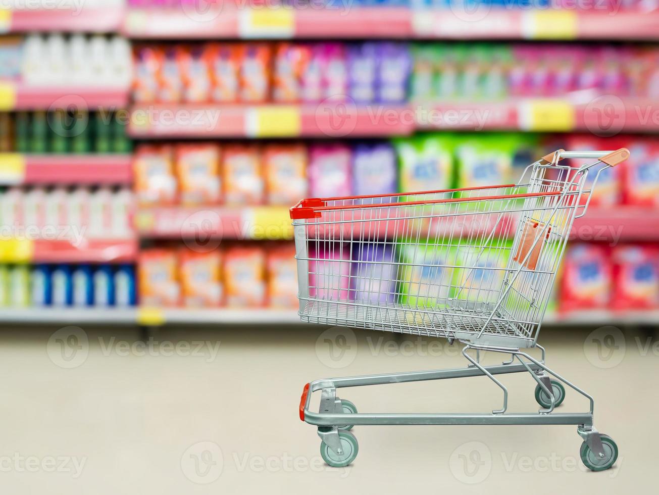 prateleiras de detergente no supermercado ou mercearia com carrinho de compras vazio foto