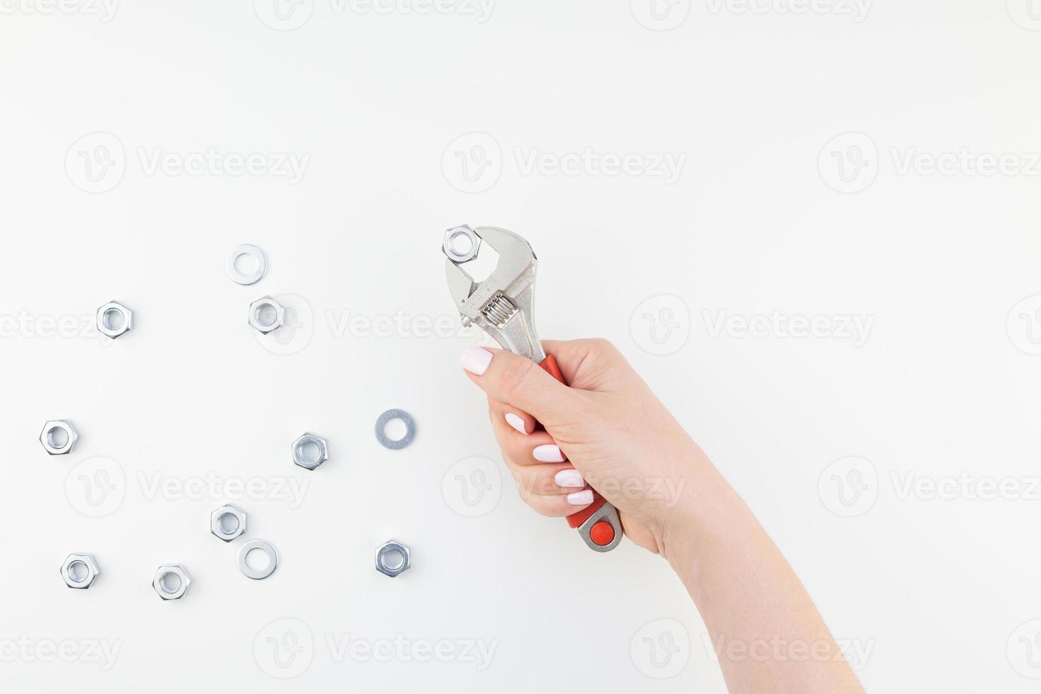 mão feminina segurando a chave inglesa no fundo branco foto