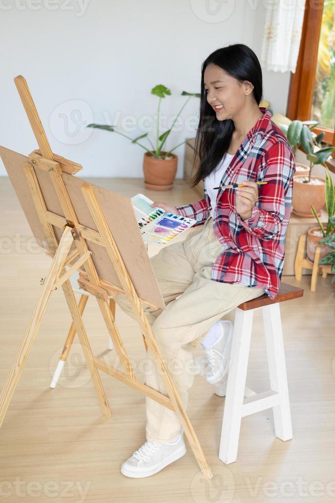 jovem pintando em papel em casa, moldura de madeira, hobby e estudo de arte em casa. foto