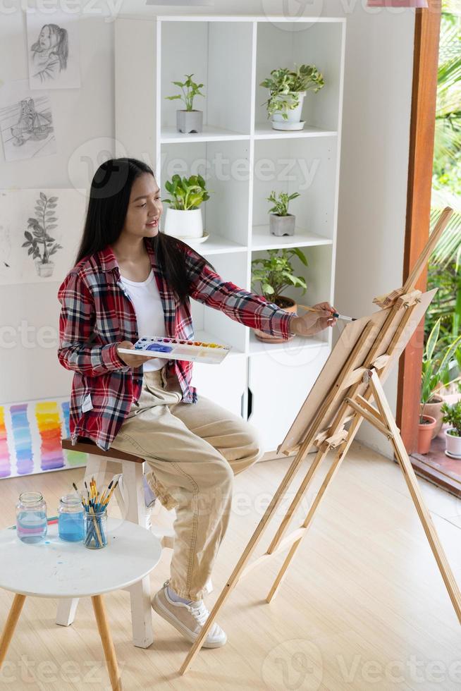 jovem pintando em papel em casa, moldura de madeira, hobby e estudo de arte em casa. foto