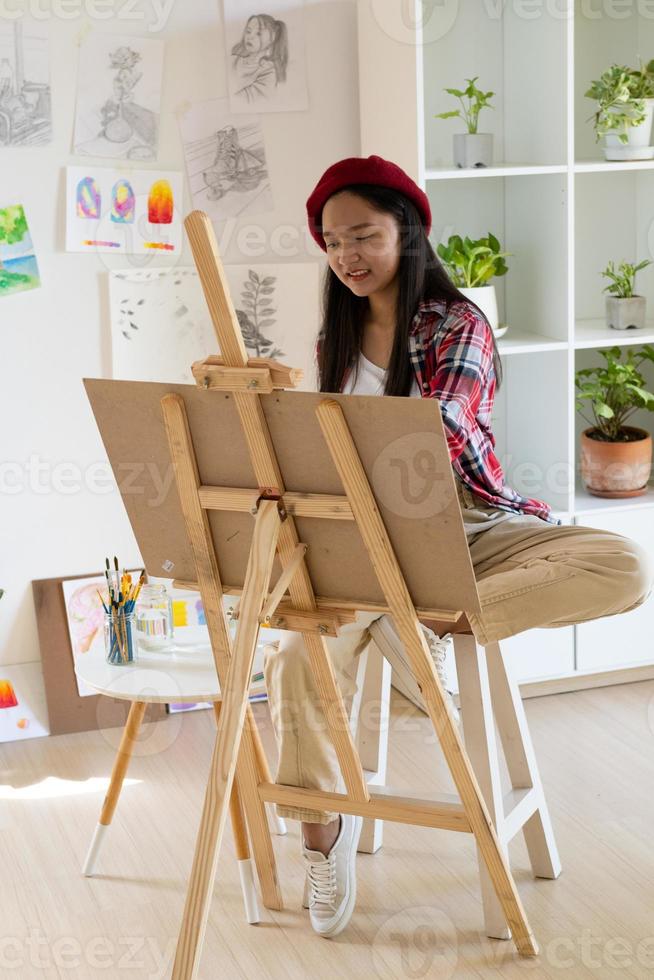 jovem pintando em papel em casa, moldura de madeira, hobby e estudo de arte em casa. foto