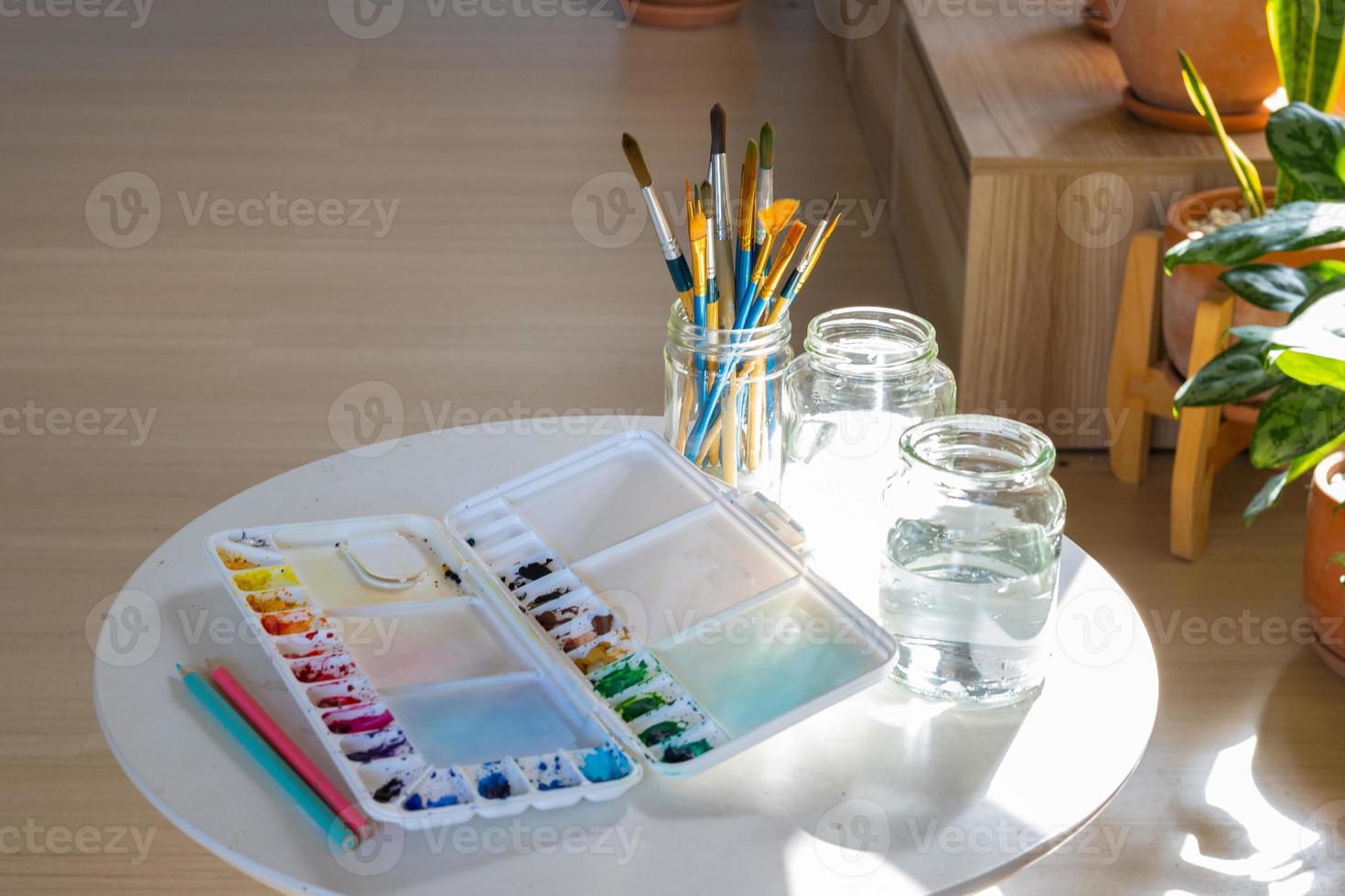 a paleta de cores, pincel e garrafa de água colocados na sala do estúdio de arte. foto