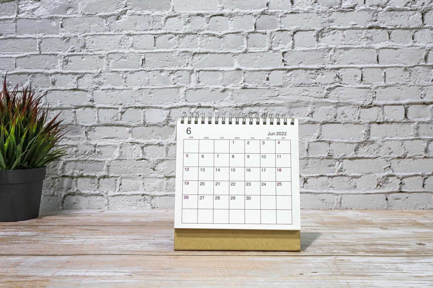 calendário branco de junho de 2022 com vaso de plantas na mesa de madeira. foto