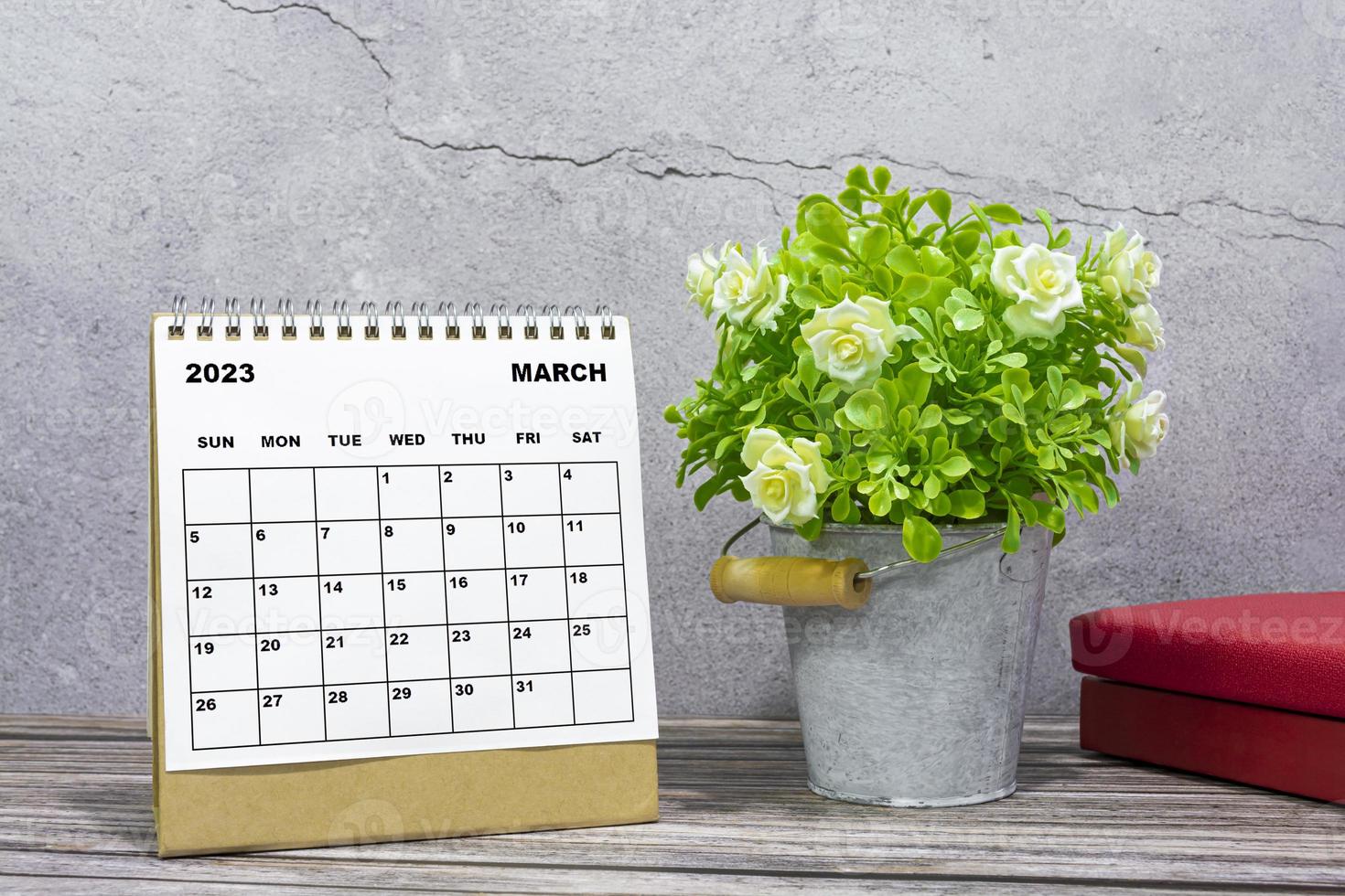 calendário de mesa de março de 2023 na mesa de madeira com vasos de plantas e livros. foto
