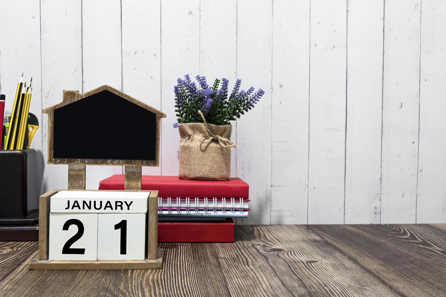 texto de data de calendário de 21 de janeiro no bloco de madeira branco com artigos de papelaria na mesa de madeira foto