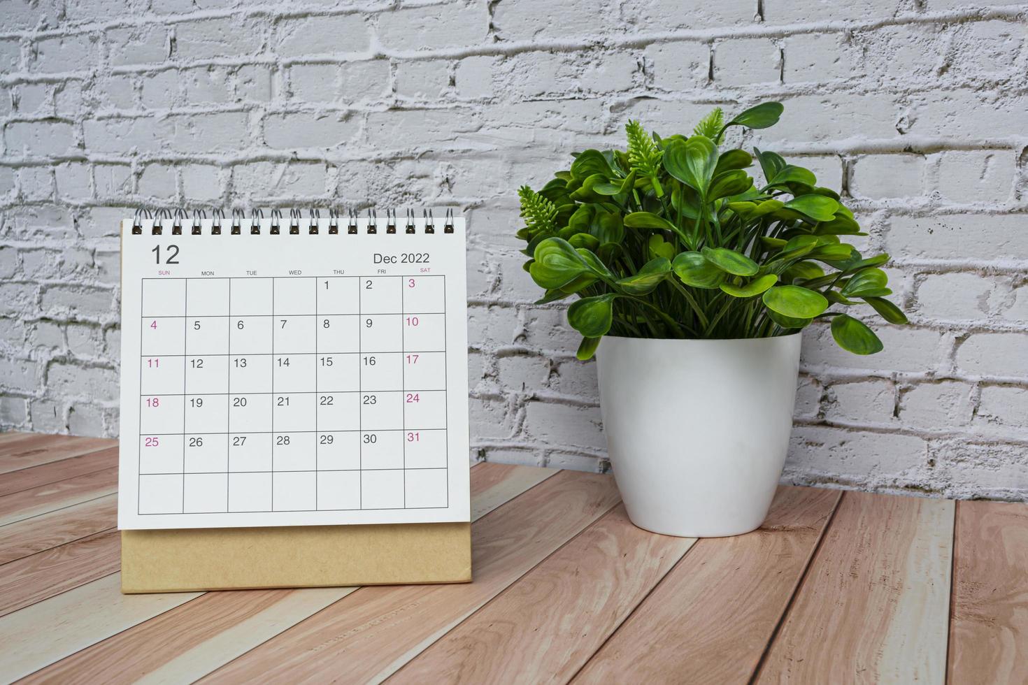 calendário branco de dezembro de 2022 com vaso de plantas na mesa de madeira. foto