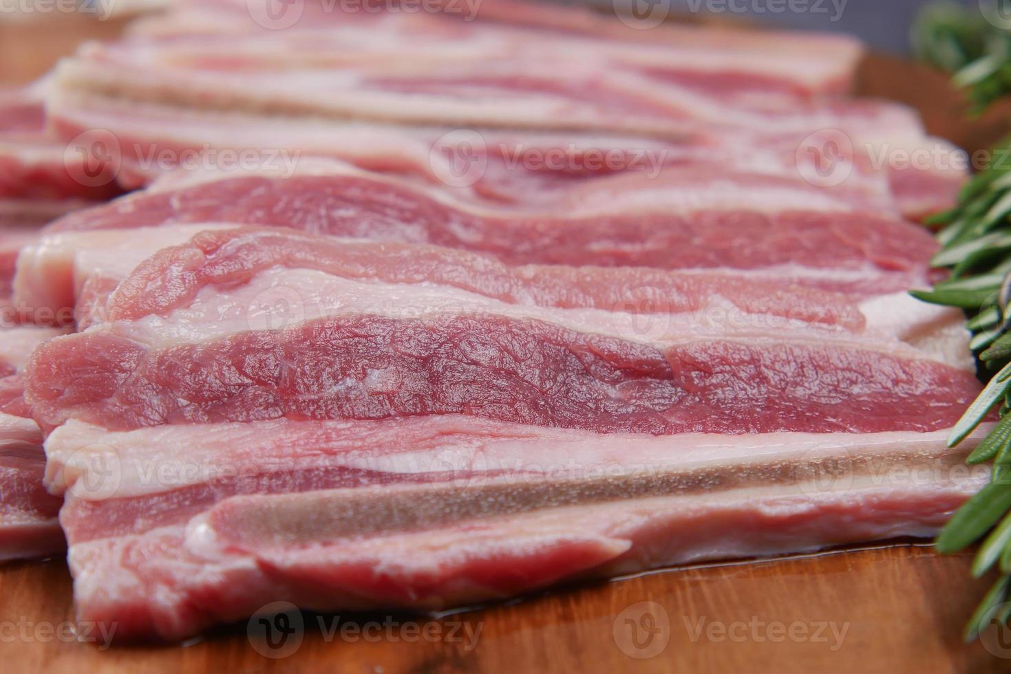 tiras de bacon cru alimentadas na tábua de cortar. foto