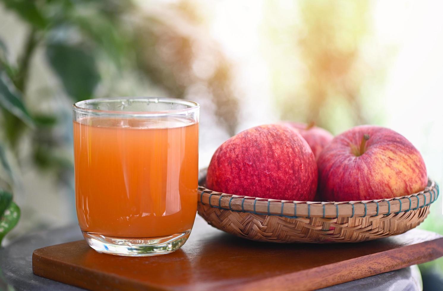 Remédios naturais de vinagre de maçã e curas para condições de saúde comuns, vinagre de maçã orgânico cru e não filtrado em vidro com frutas de maçã na mesa de madeira foto