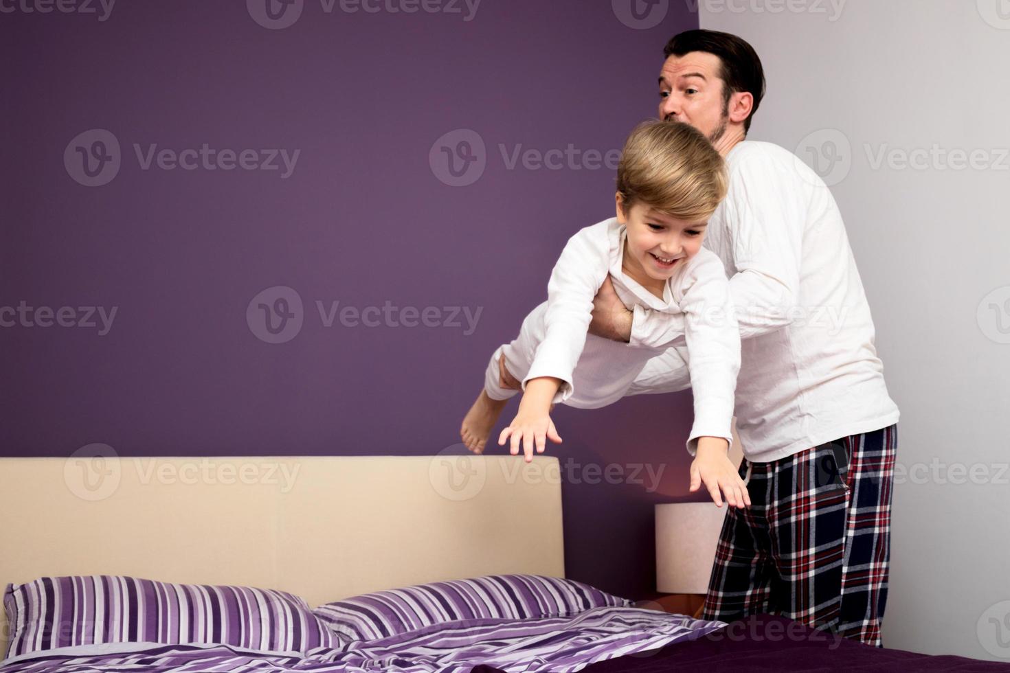 homem feliz brincando com seu filho no quarto. foto