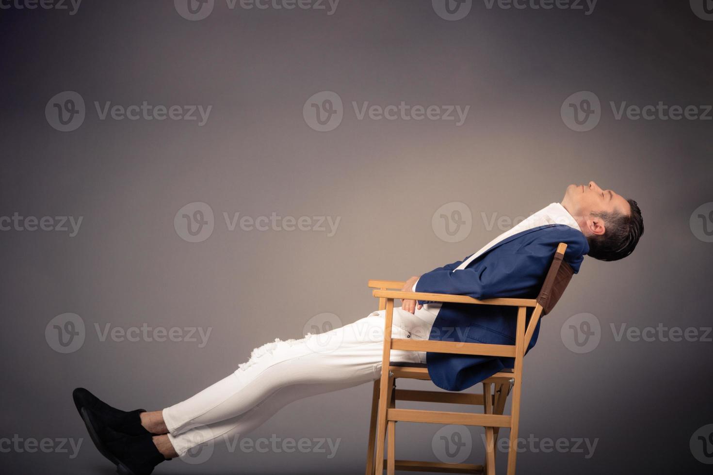 empresário descansando na cadeira contra a parede vazia. foto