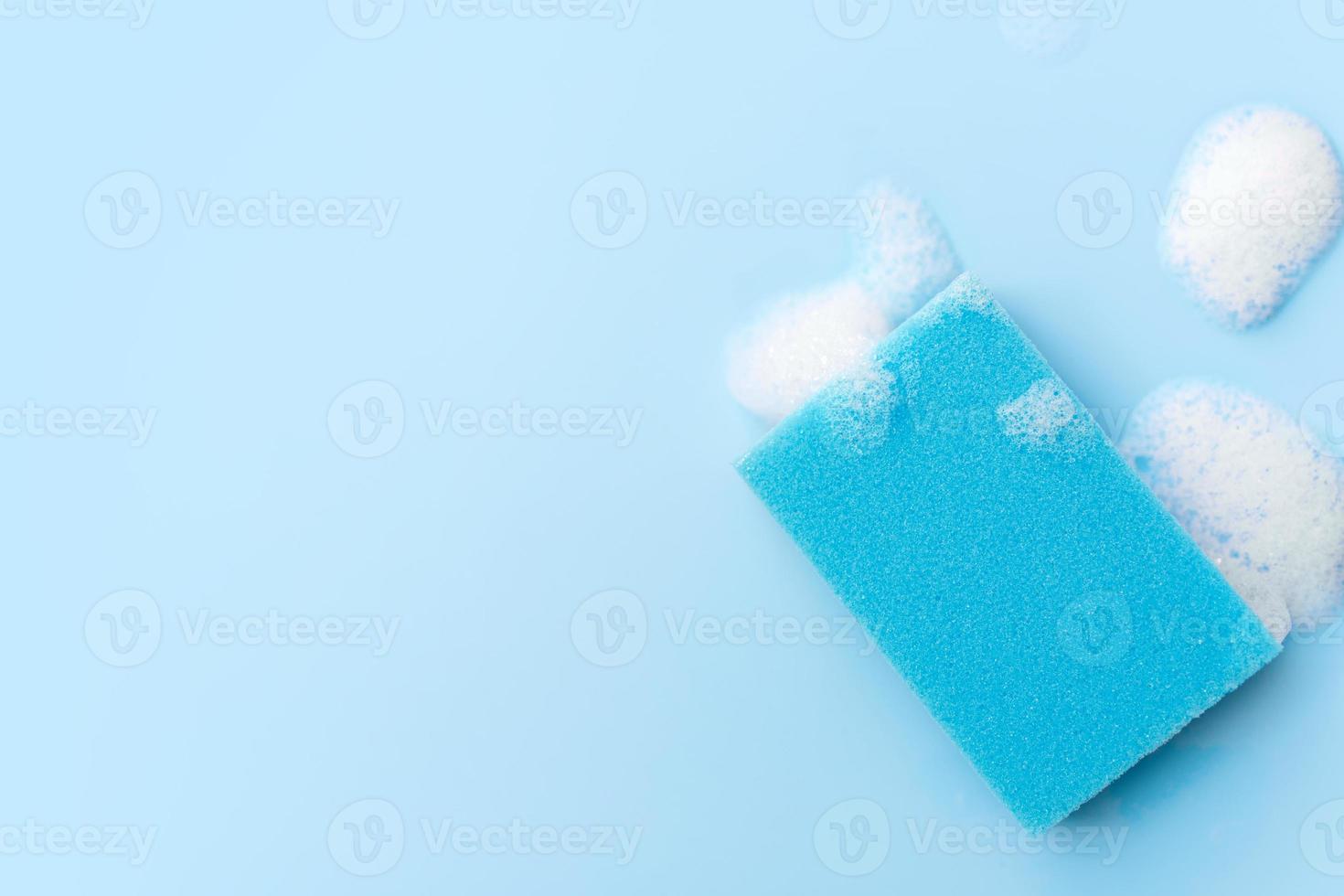 esponjas multicoloridas para limpeza em um fundo azul. espaço para texto. foto