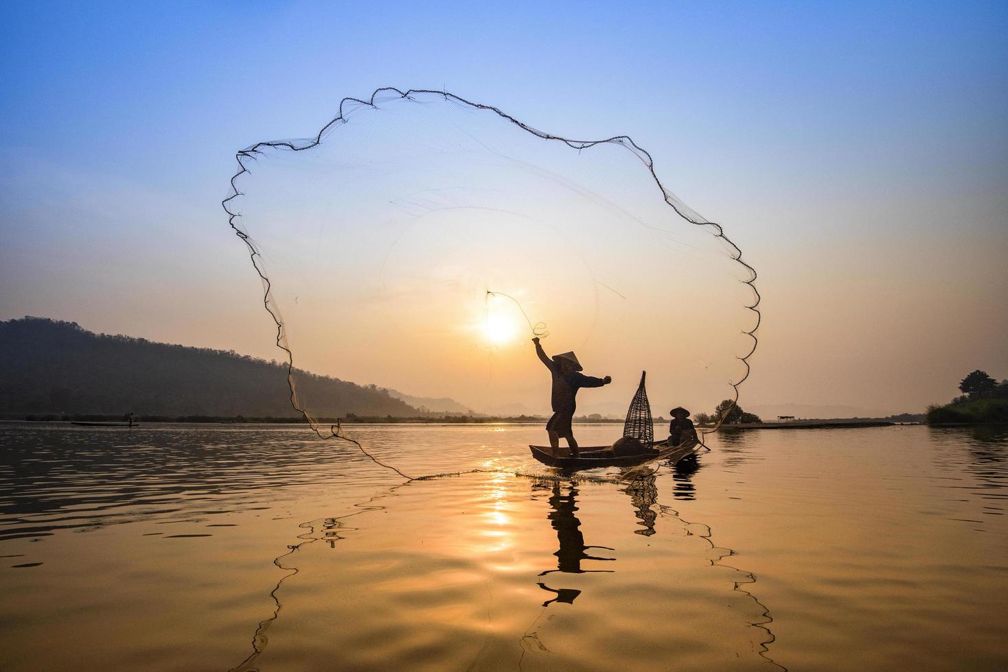 rede de pescador da ásia usando na rede de fundição de barco de madeira pôr do sol ou nascer do sol no rio mekong foto