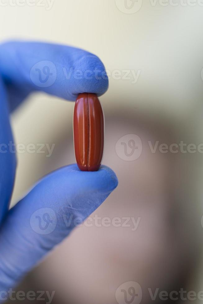 mulher segurando cápsulas de comprimidos vermelhos foto
