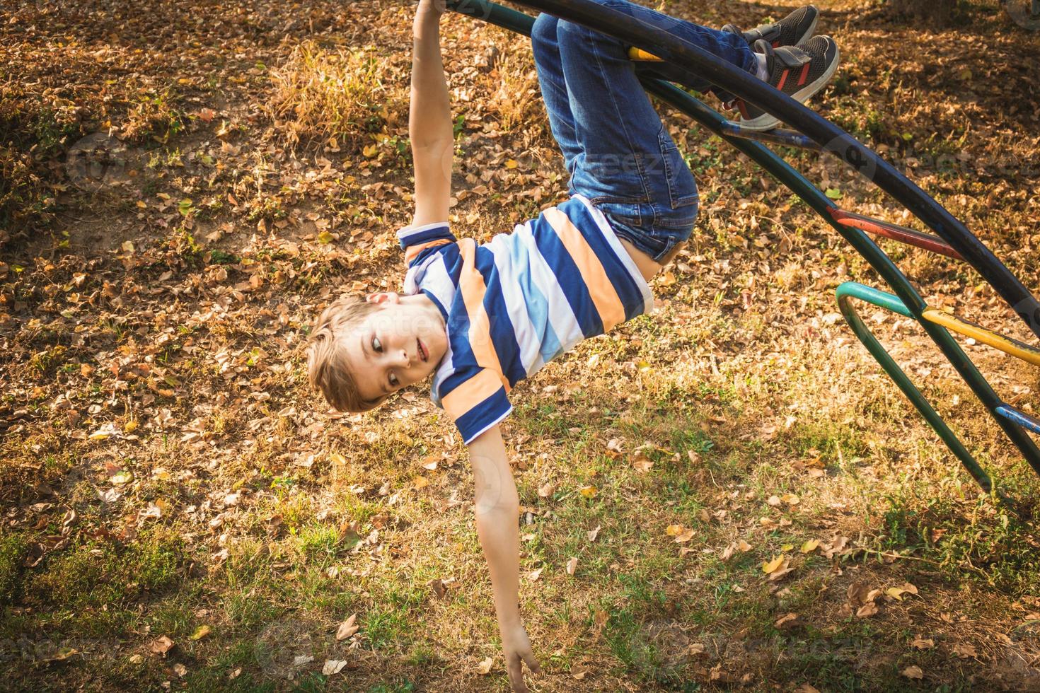 menino pequeno menino brincando no playground no parque. foto