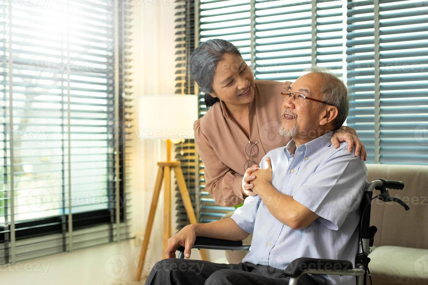 casal de idosos de mãos dadas após a aposentadoria, marido esposa pessoa cuida um do outro em um momento romântico com sorriso feliz. avó asiático sente-se na cadeira de rodas olhando, copie o espaço foto