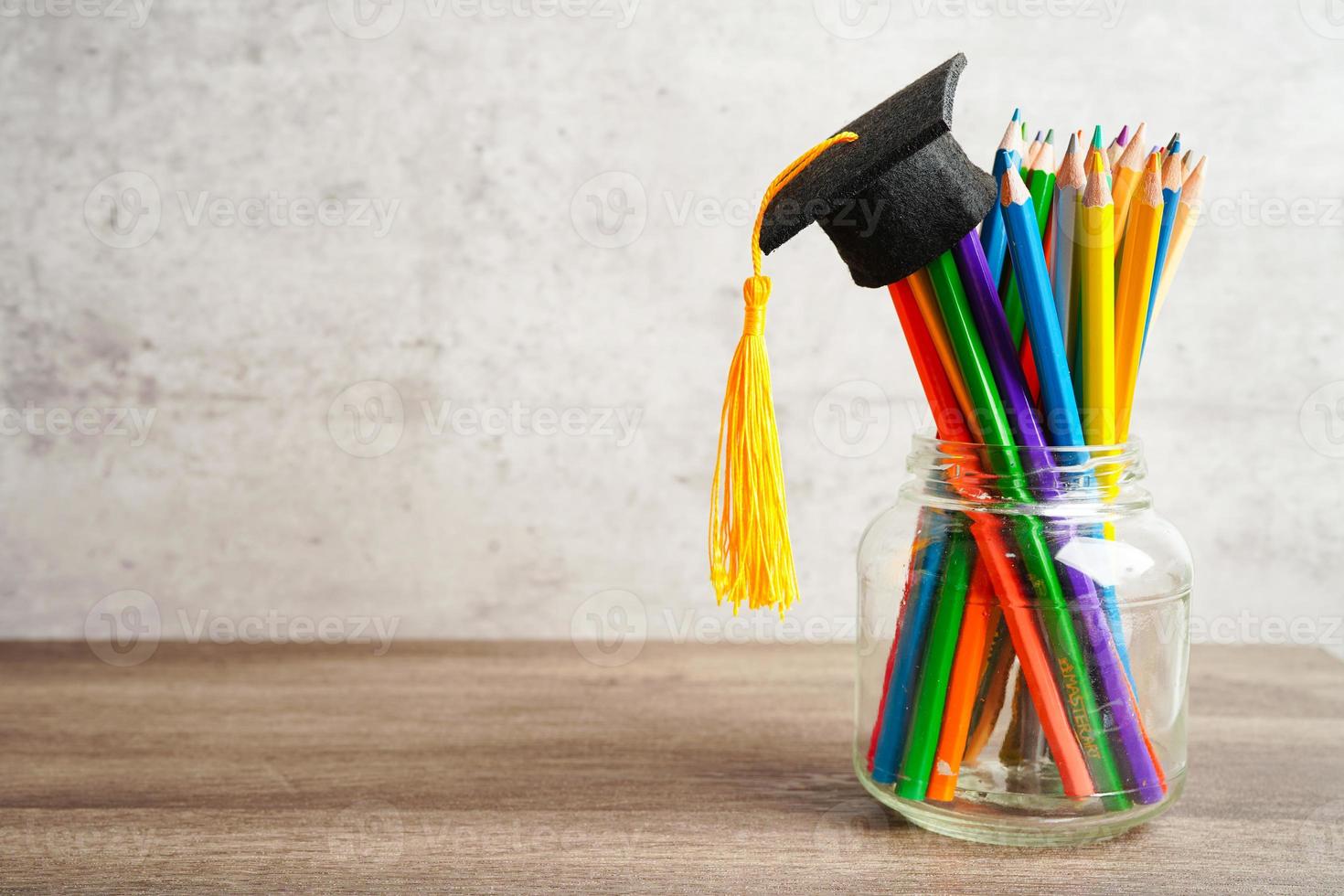 chapéu de formatura com lápis coloridos no livro com espaço de cópia, aprendendo o conceito de educação universitária. foto