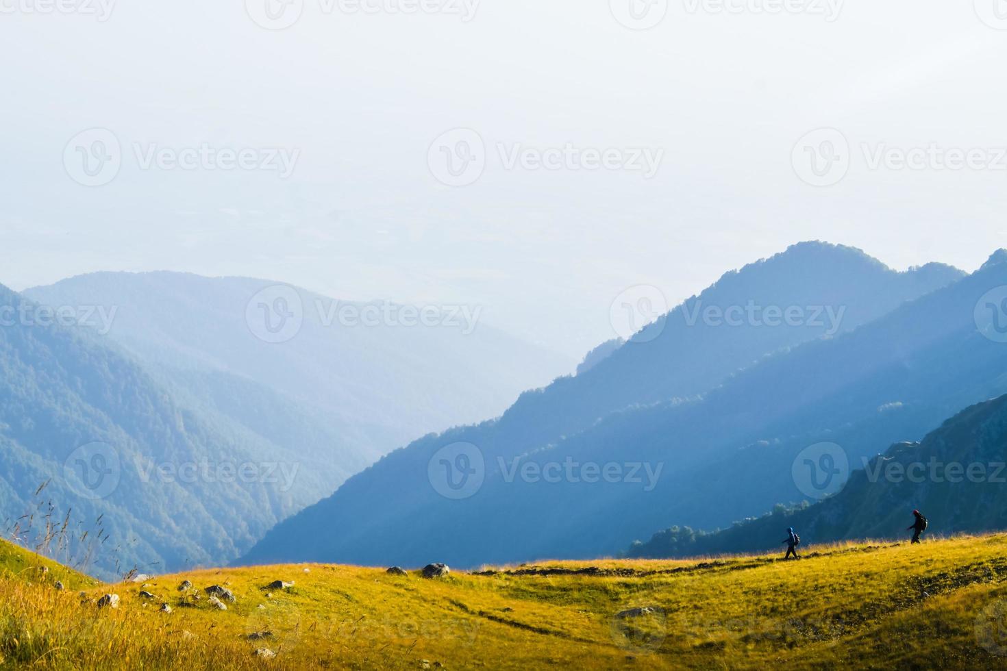 dois amigos do sexo masculino caminhantes em caminhada de distância na trilha ao ar livre no belo pôr do sol no outono juntos. pessoas ativas em caminhada nas montanhas do cáucaso foto