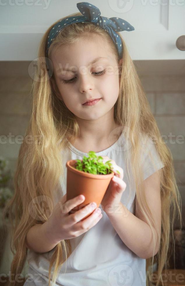 menina segurando um pote de mudas foto