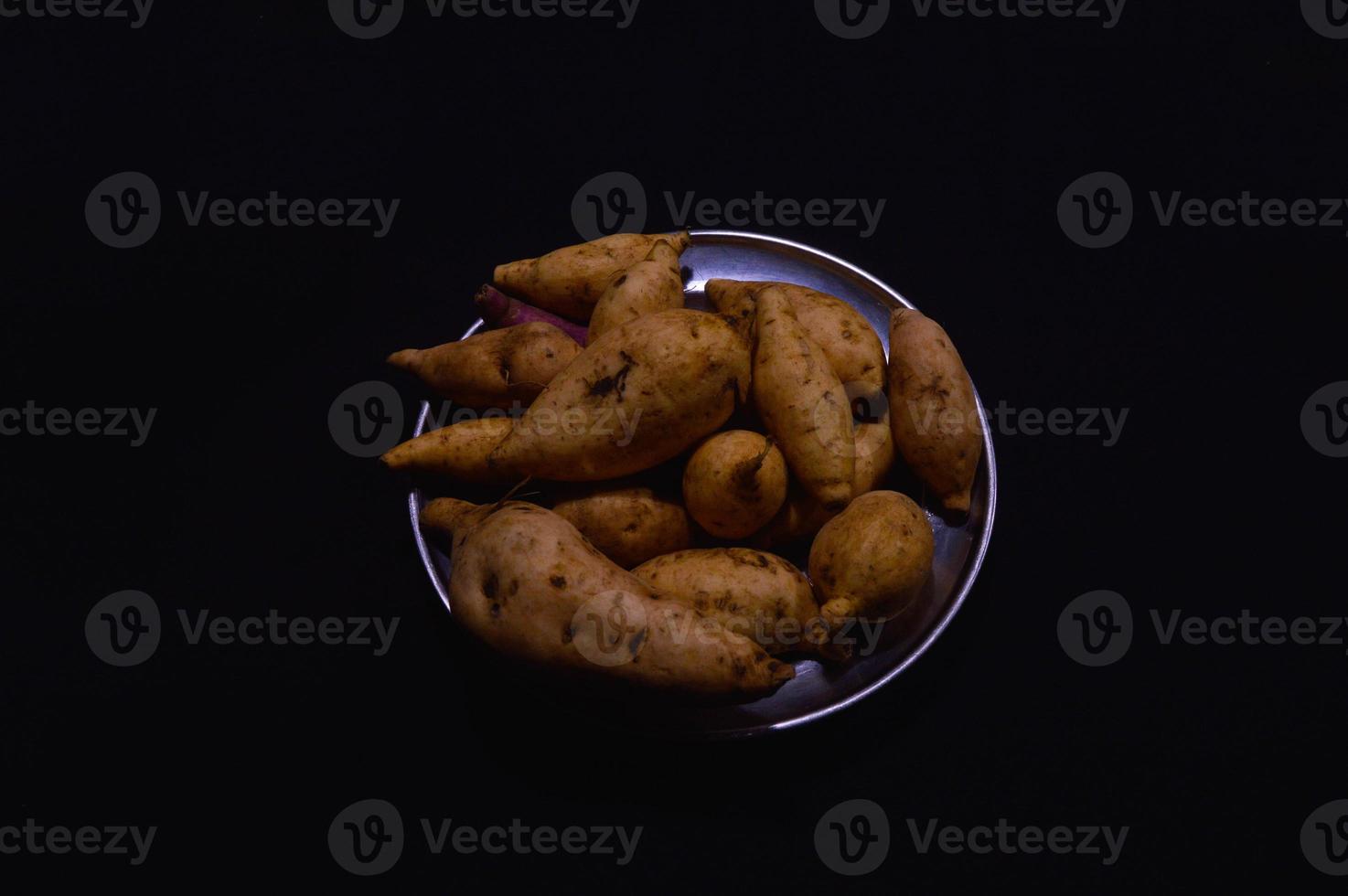 batata-doce em um prato em um fundo preto foto