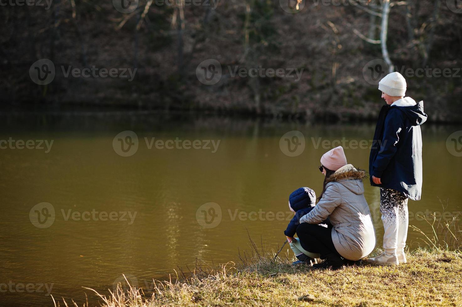 mãe com filhos pescando com uma vara em libra no parque de início da primavera. foto