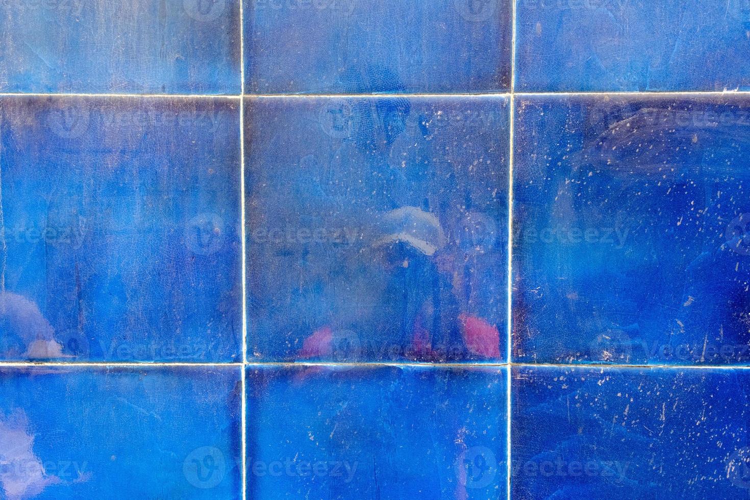 reflexão de uma pessoa com uma câmera na parede de azulejo líquido azul, textura grunge e padrão, abstrato. foto