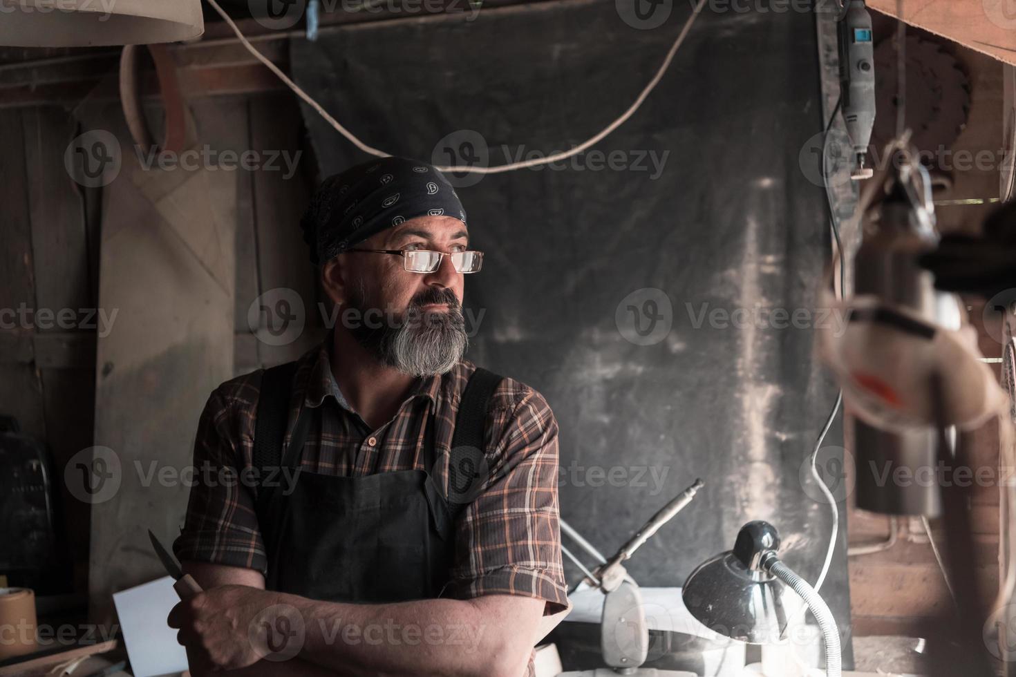 mestre de artesanato de colher em sua oficina com ferramentas e produtos artesanais de madeira foto