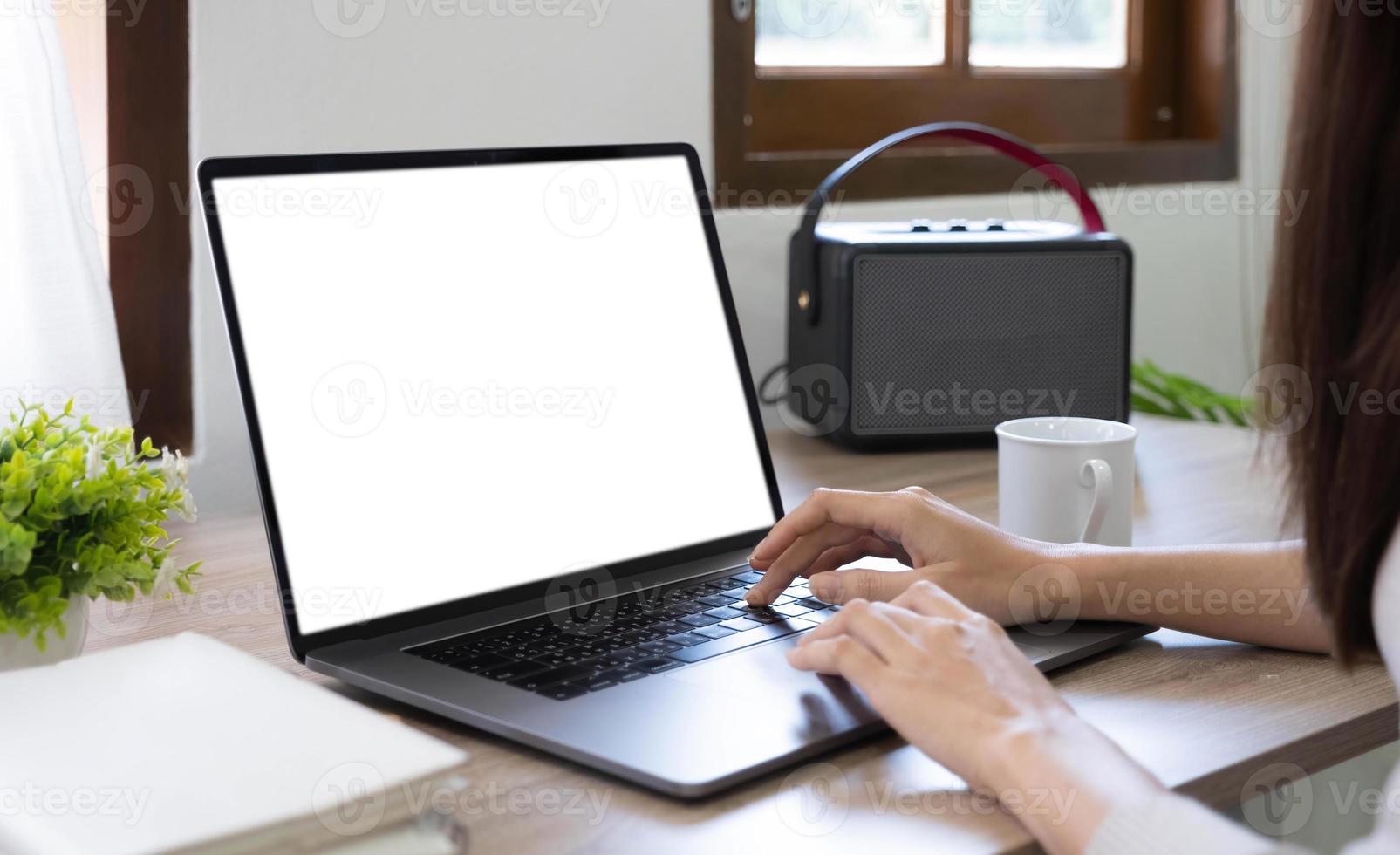 maquete em branco da tela do computador. A mão da mulher trabalha usando laptop com fundo branco para publicidade, informações de pesquisa de negócios na mesa do café. foto