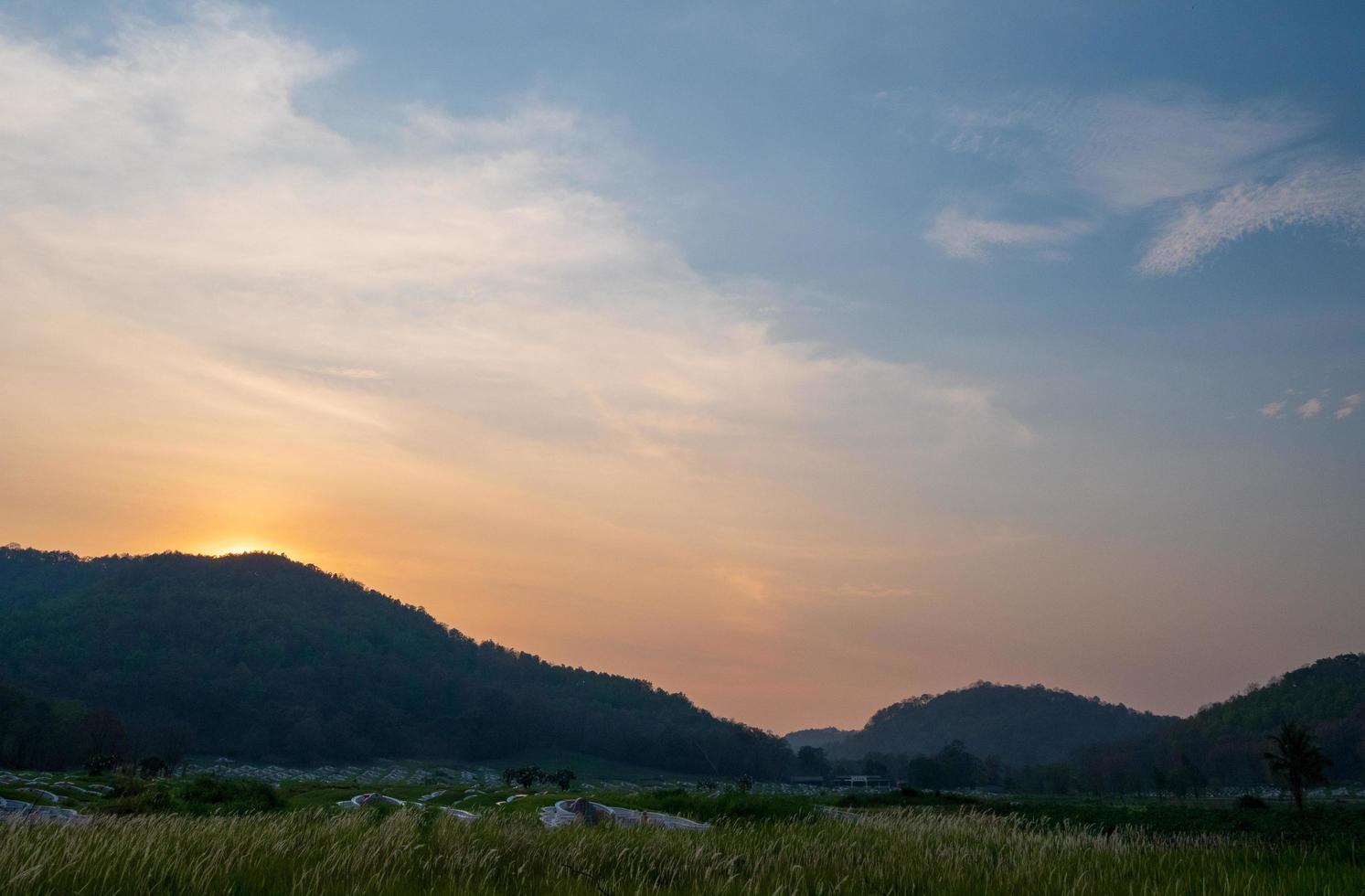 vista da paisagem montanhas com árvores verdes laranja luz dourada do pôr do sol com nevoeiro aconteceu depois da chuva durante as horas da noite do dia é silhueta preta olhar para belas cores e natureza. foto