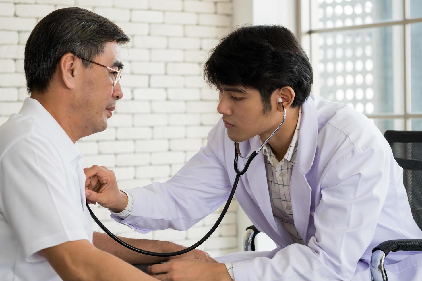 jovem médico masculino verificando a saúde do paciente sênior no quarto do hospital. foto