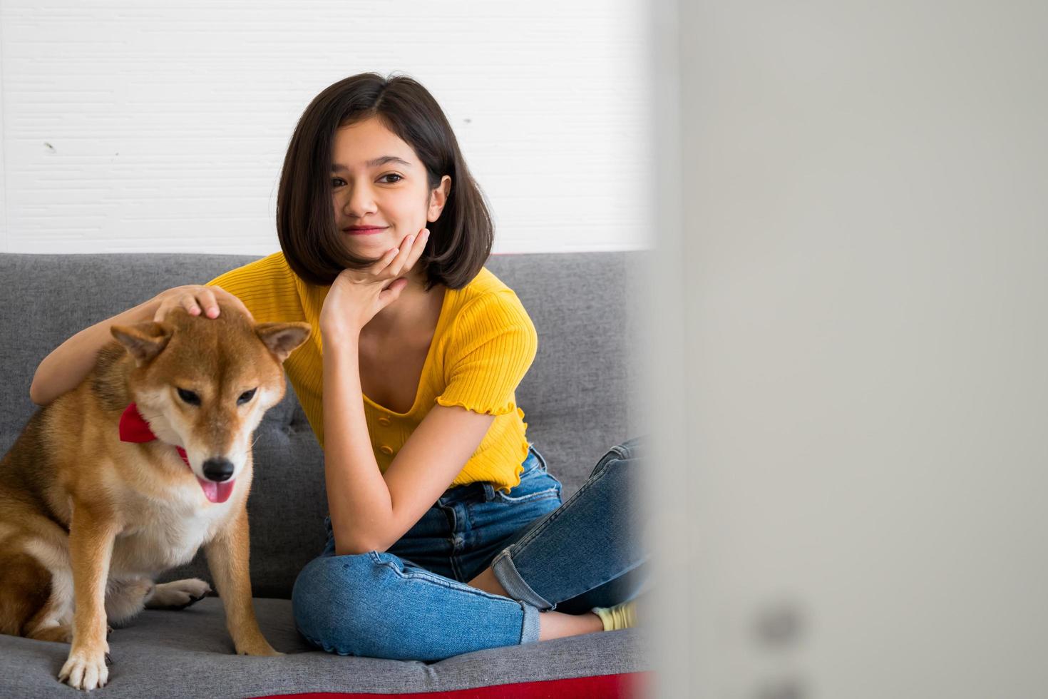 mulher feliz e cachorro shiba inu sentados juntos em um sofá em casa foto