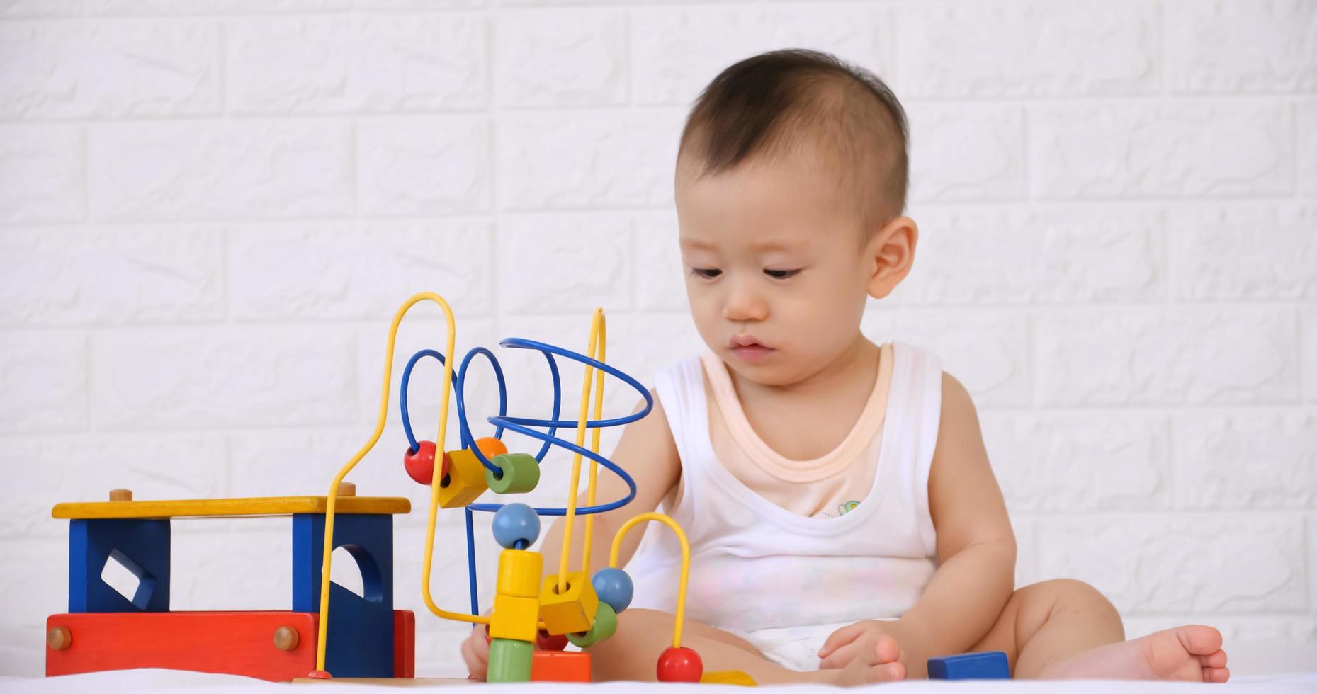 adorável bebezinho jogando um brinquedo na cama. foto