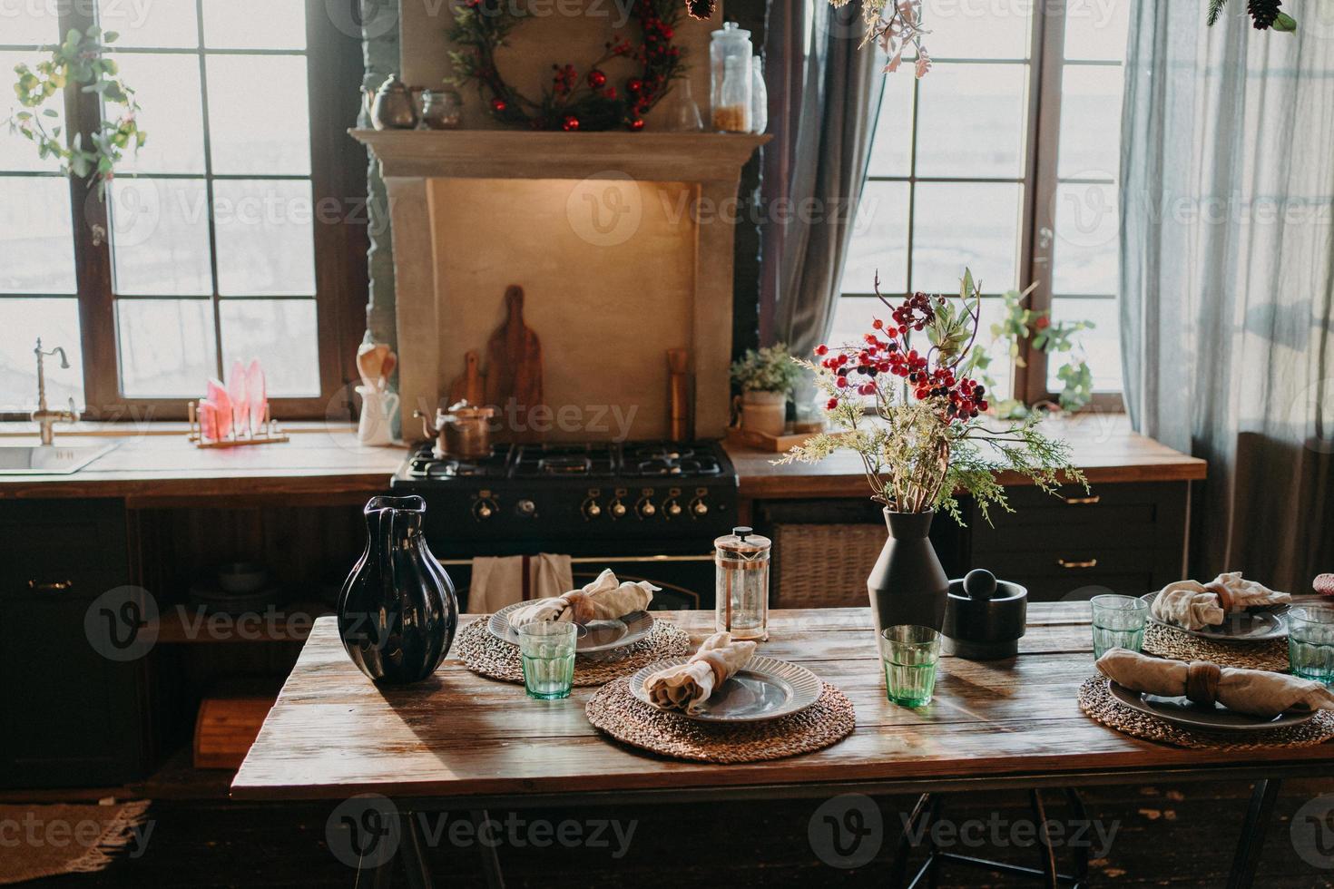 interior da cozinha. servido mesa de jantar com decoração floral de copos de pratos. talheres e copos. preparação para o jantar festivo. arranjo de mesa para jantar em família foto